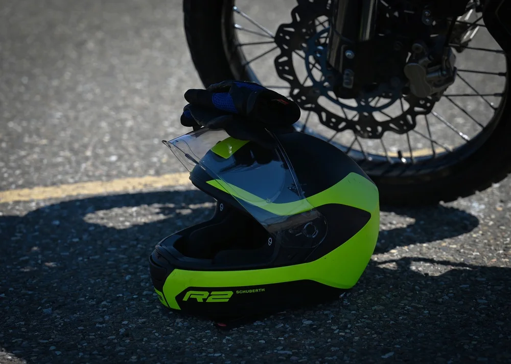 A full-face motorcycle helmet and riding gloves beside a motorcycle wheel at a safety training course