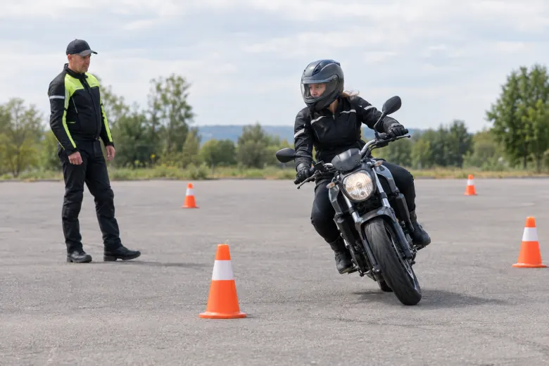 Rider practising a low-speed turn around training cones with an instructor