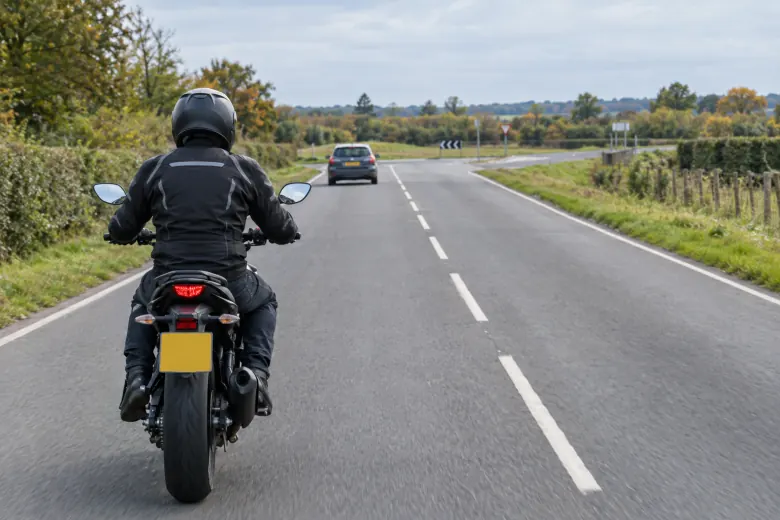 Motorcyclist approaching a road junction with a car ahead