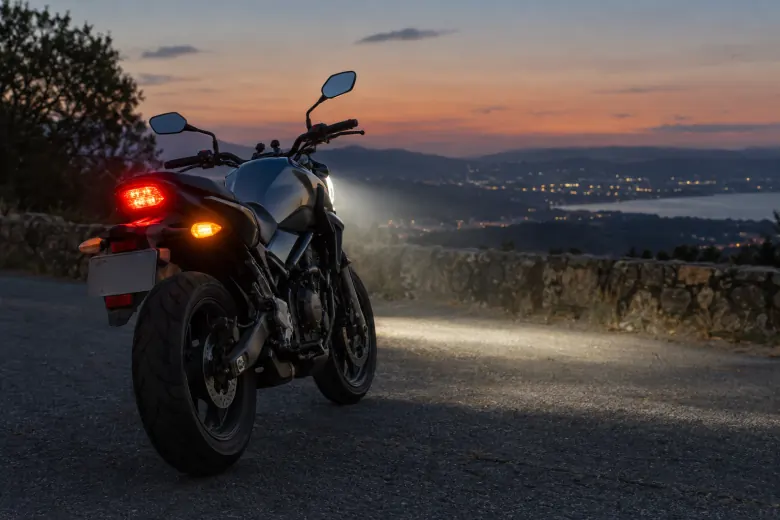 Rear light and indicator illuminated on a parked motorcycle at dusk
