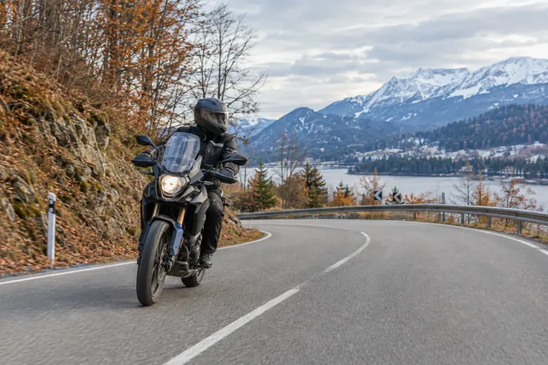 Motorcyclist on a clear mountain road with snow on distant slopes